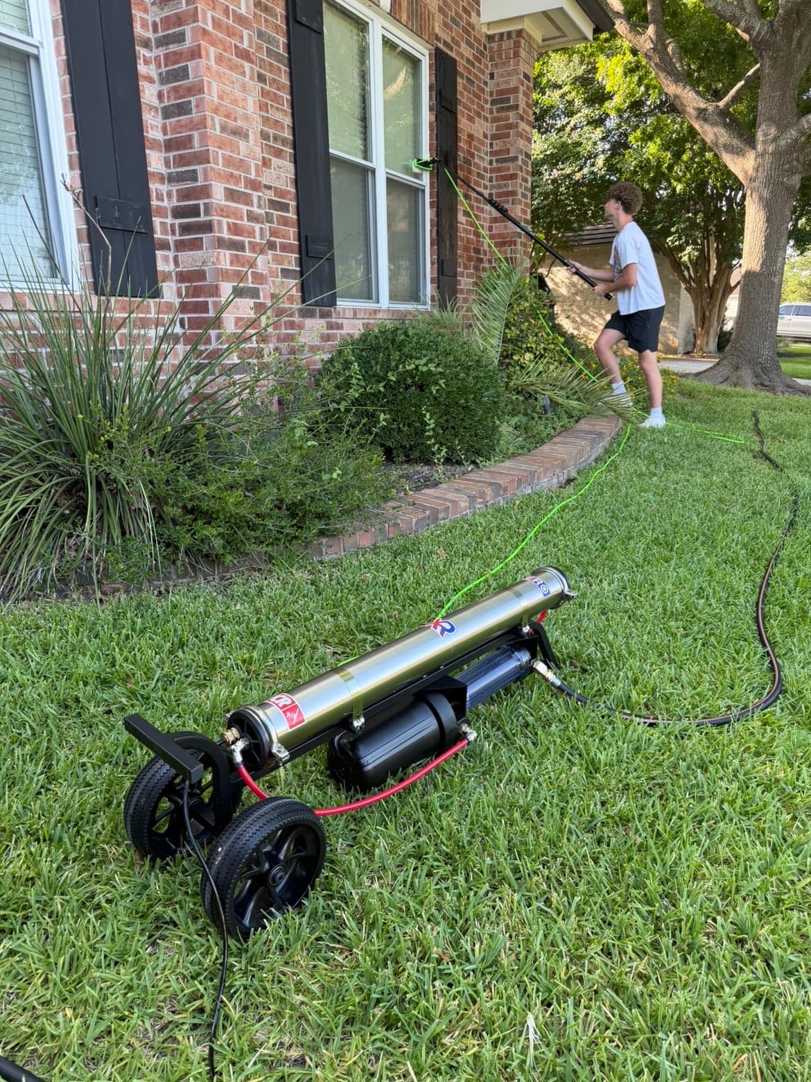 A New Wave Exterior technician exterior window cleaning with a water-fed pole system reaching a second-story window